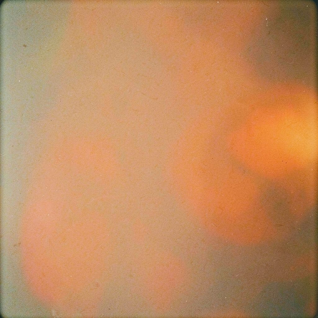 Analog film photograph showing pilgrims gathered near a sunlit plaza, faded golden tones and gentle film grain
