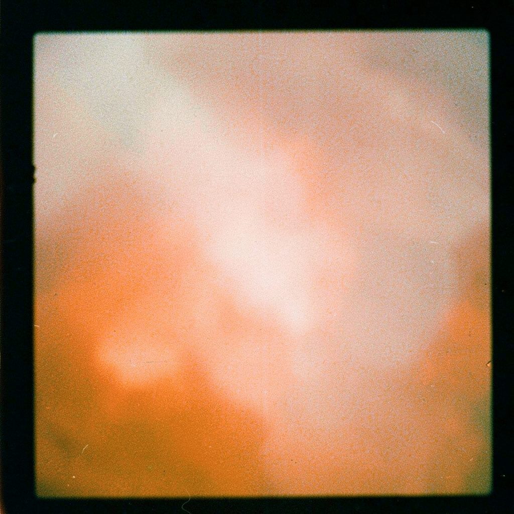 Atmospheric analog film photograph of a northern Mexican cityscape under a wide open sky, warm sepia and gray tones with visible grain.